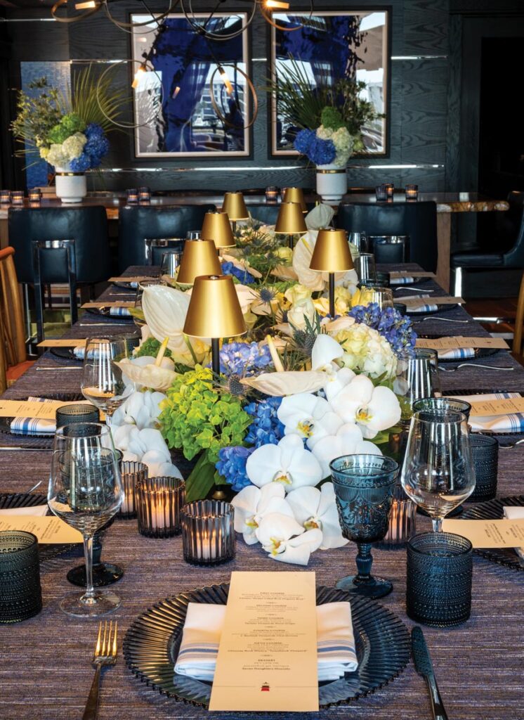 The centerpiece featured white phalaenopsis orchids, blue thistle, white ranunculus, white roses, mini monstera, and green, blue, and white hydrangeas. Photo by Jerry Rabinowitz